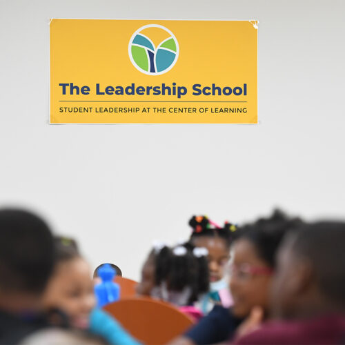 Yellow sign of The Leadership School on white wall
